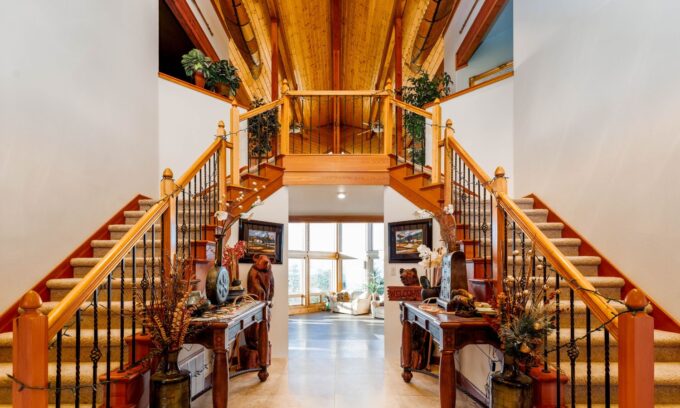Elegant wooden staircase with double handrails leading to a loft in a luxury home.